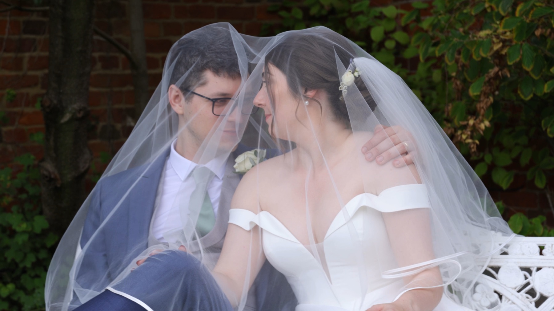 A bride and groom sheltering under her veil, from one of our wedding films
