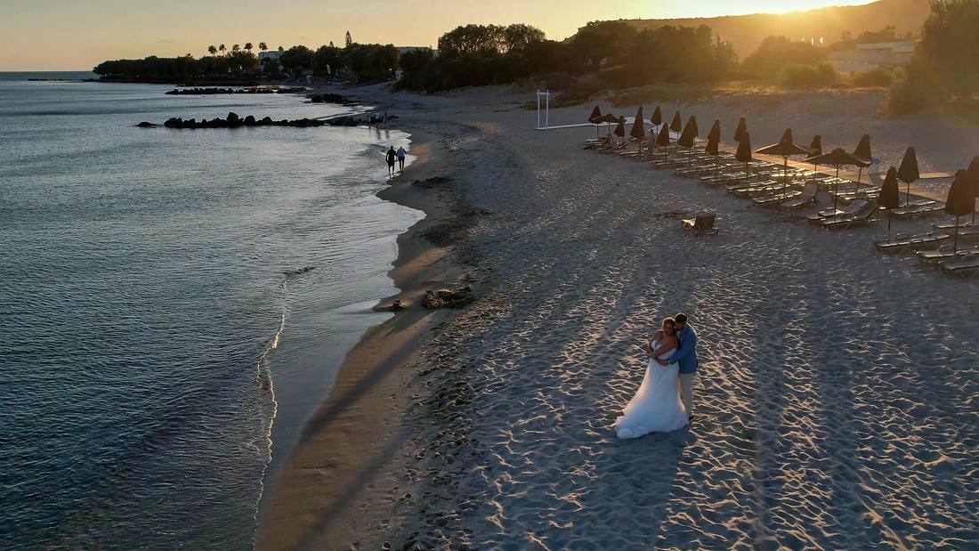 Drone view of a couple dancing on a beach at sunset