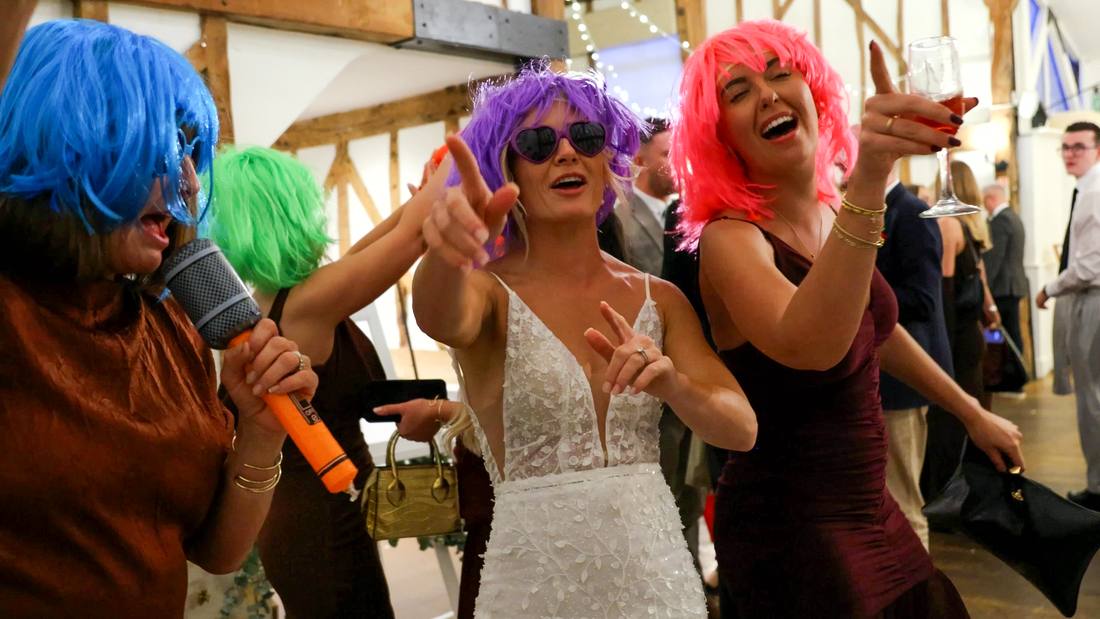 Guests in bright wigs singing along at a reception