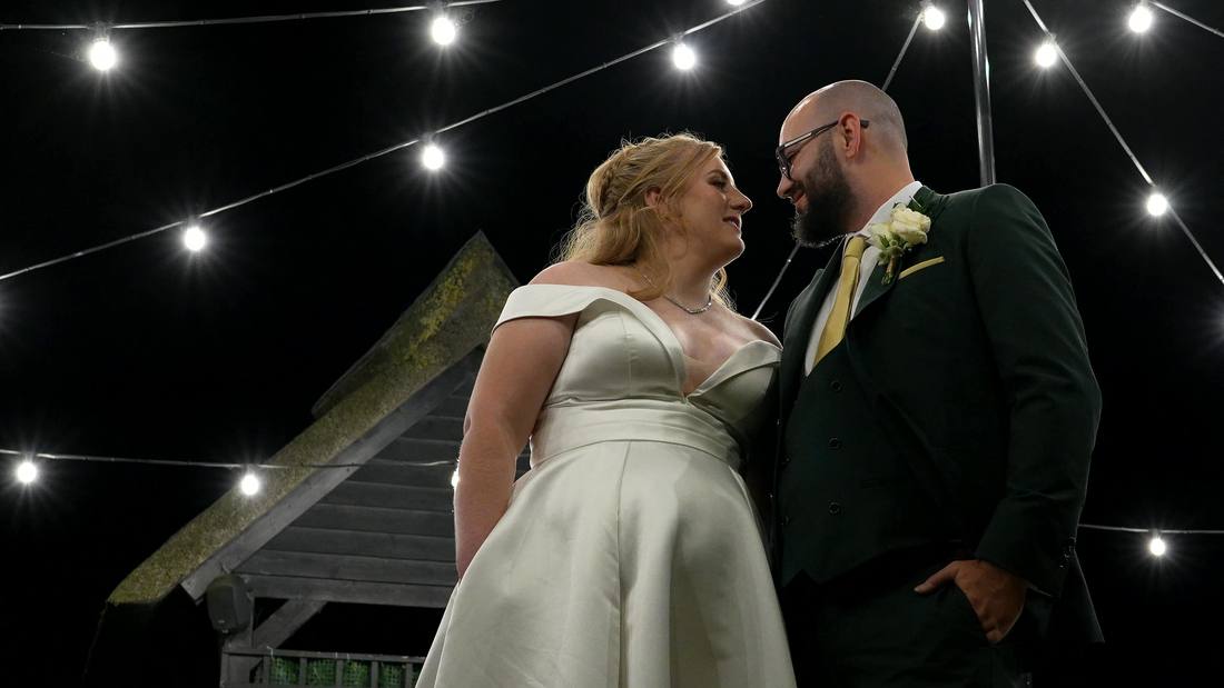 A couple under festoon lights at night